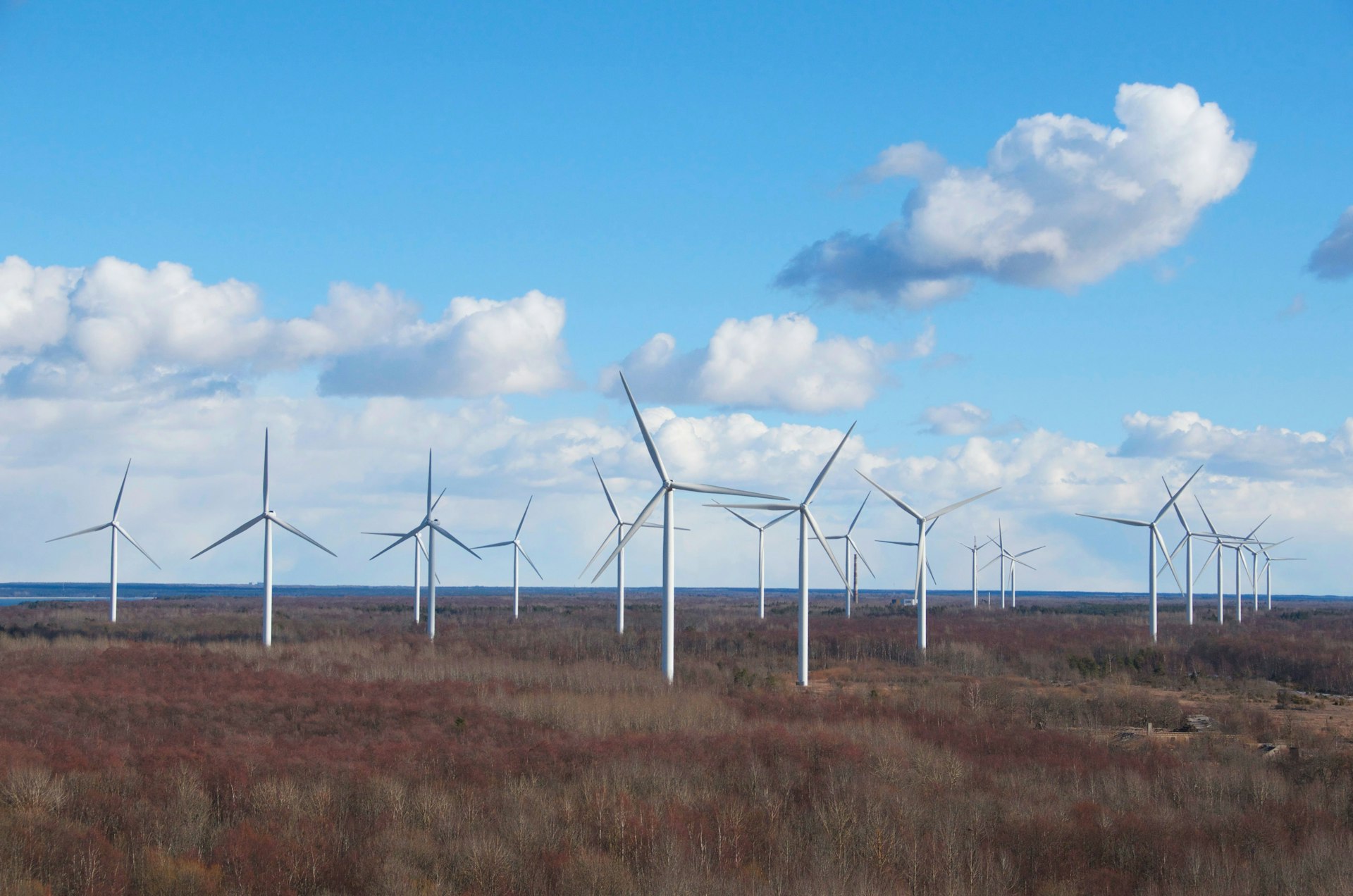 Wind turbines stand in a field under a cloudy sky.